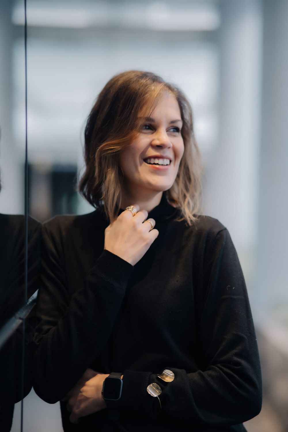 Rebbeca Rödel sorrindo, com a mão no colarinho do suéter preto